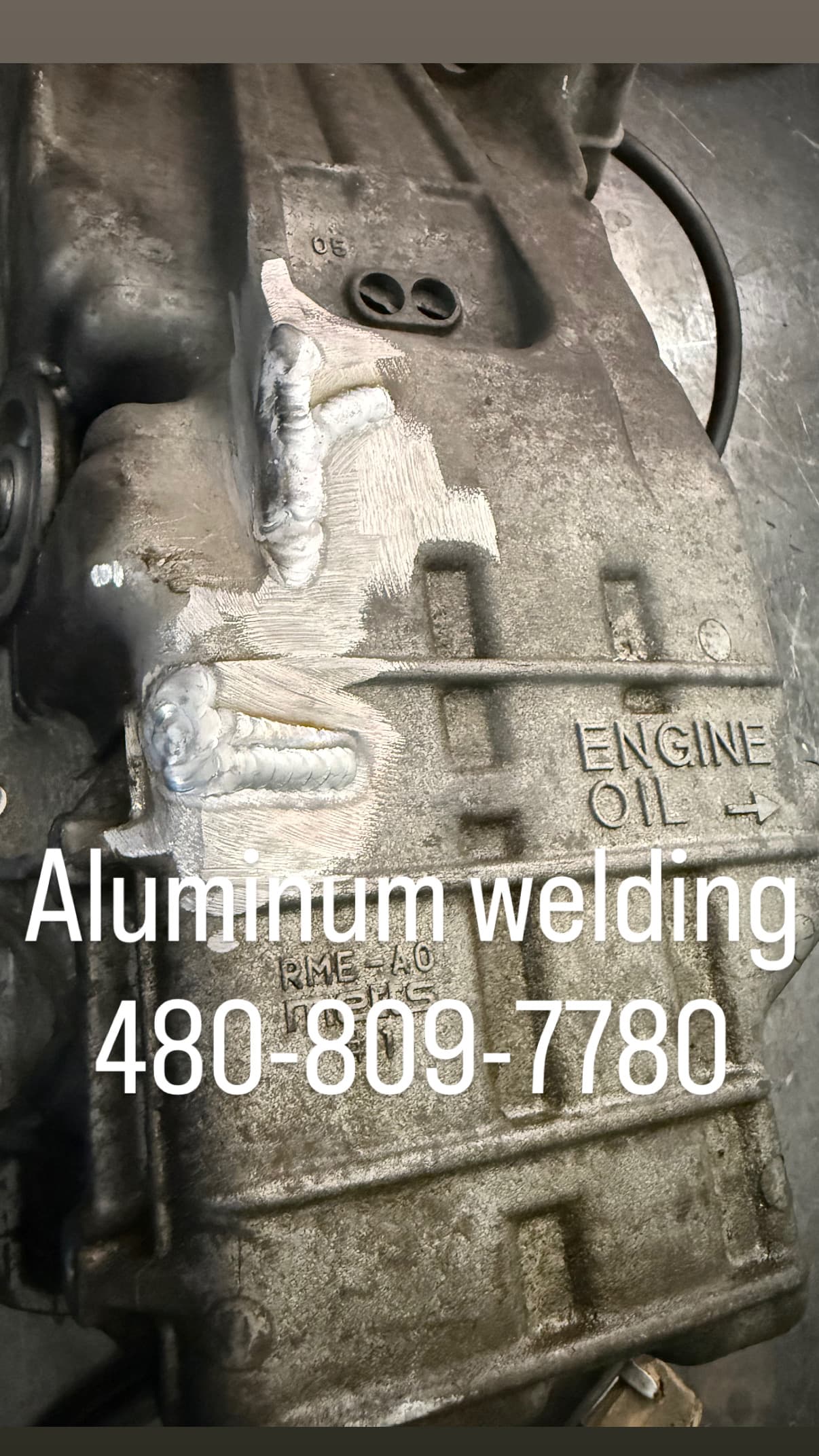 Fresh aluminum welds on an engine oil pan with service contact information text overlay.
